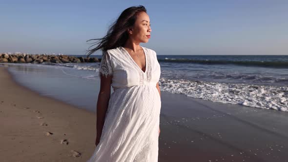 Pregnant Asian woman enjoying walk on the beach