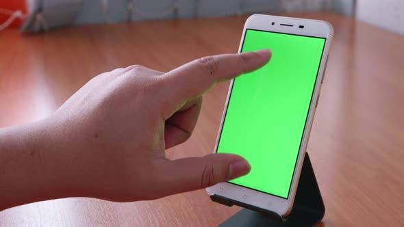 Slide motion of the male hand is sliding and touching the phone with the green screen is placed on t