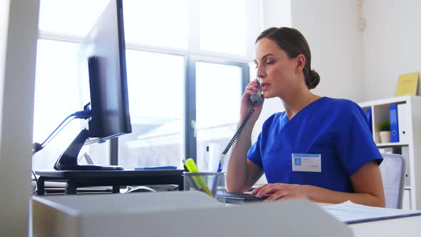 Doctor with Computer Calling on Phone at Hospital