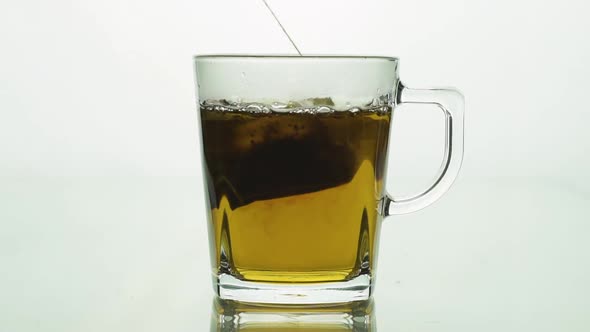 Man’s Hand Lifting and Dropping Black Tea Bag Into Glass Transparent Mug To Brew Tea Isolated on