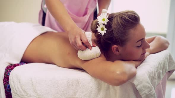 Massage Therapist Using Herbal Compress on Woman