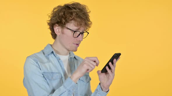 Redhead Young Man Using Smartphone Yellow Background