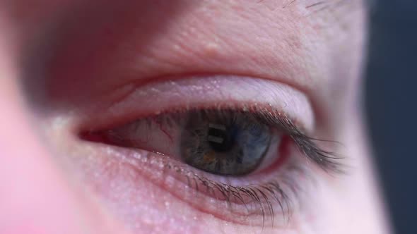 Reflection of screen on person's blue green eye in dark room 8