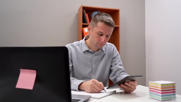 Young Male Office Worker Holding a Tablet in His Hands in Remote Work