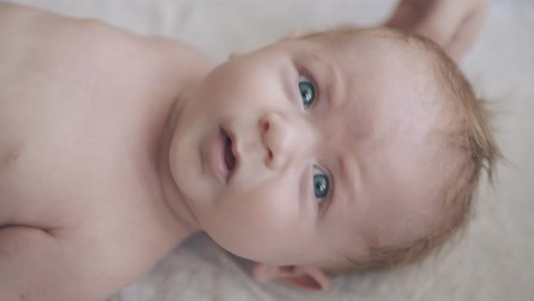 Infant Son with Big Blue Eyes and Fair Hair Looks at Camera