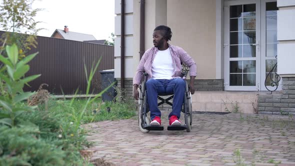 Wide Shot Troubled Stressed African American Man Rolling Wheelchair Talking Holding Head in Hands