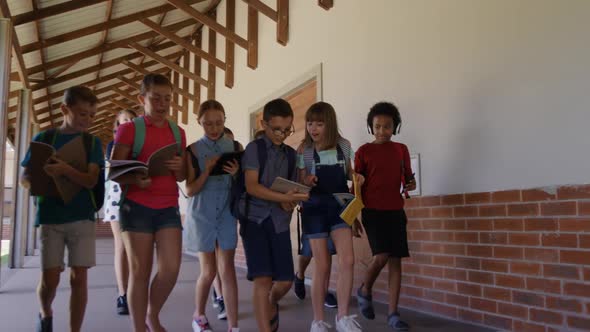 Group of kids with books walking in the school corridor
