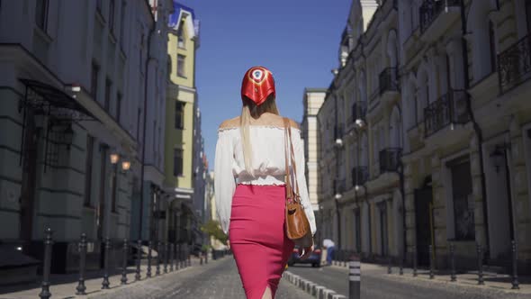 Back View of Beautiful Young Woman Walking on the Street, Turning and Looking at the Camera Making