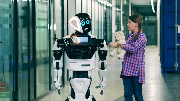 Teenage Girl Is Talking To a Droid and Showing It Her Teddybear