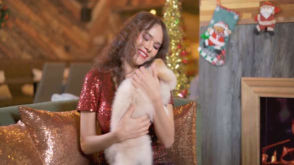 Asian young smiling woman sitting in cafe restaurant hugging and kissing lovely pomeranian dog