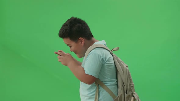 Asian Boy Student Playing Game On Mobile Phone And Walking To School On Green Screen Chroma Key