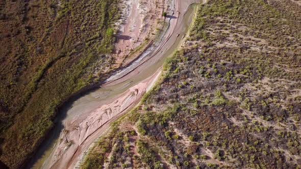 Flying aerial  view of winding river flowing through the desert