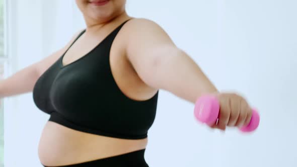 Overweight young woman in sportswear exercising to lose weight at home