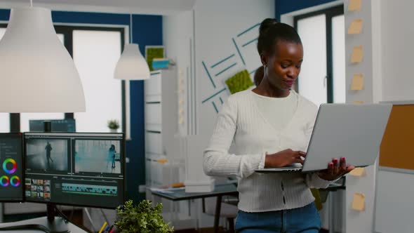 African Videographer Raising Head Smiling at Camera After Typing at Laptop