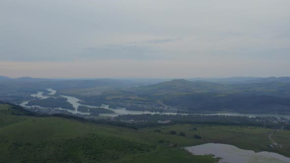 Green field and lake in valley under white clouds at during daytime