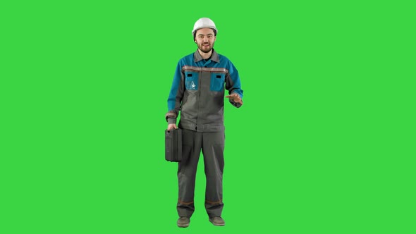 Builder in Helmet with a Suitcase Says on Camera on a Green Screen, Chroma Key