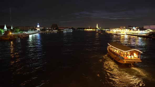 Big cruise boat with illuminated colorful lights sailing across the river at night along cityscape