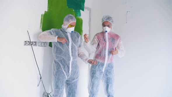 Couple in Protective Suits and Respirators in Light Room