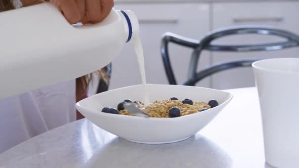 Man pouring milk in a bowl at kitchen 4k