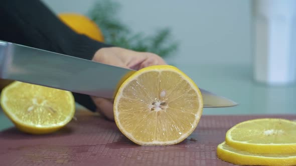 Woman slicing yellow lemon on chopping board closeup slow motion. Juicy lemon cut into slices. Cutti