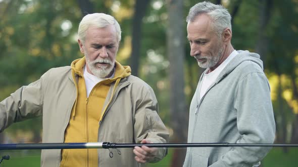 Aged Male Showing New Fishing Rod to Friend, Pensioner Hobby, Togetherness
