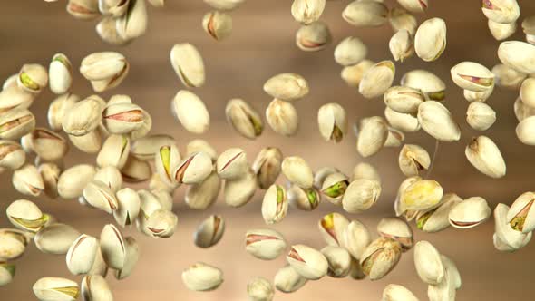 Super Slow Motion Shot of Flying Pistachios After Being Exploded on Wooden Background at 1000Fps.