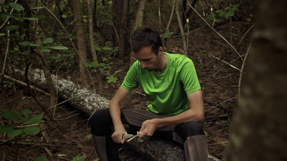 Survivalist with Knife Cut a Wooden Stick