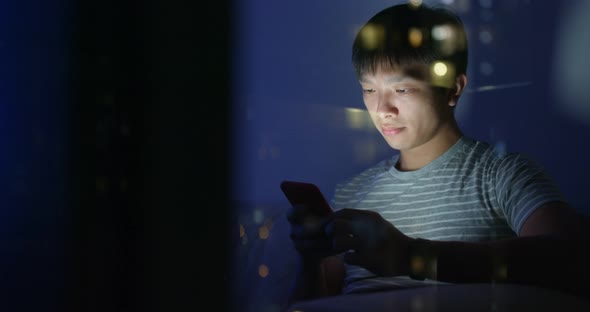 Man Use of Mobile Phone at Home with Window Reflection in The Evening