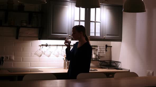 Woman Coming and Drinking Water From Glass in Kitchen at Night