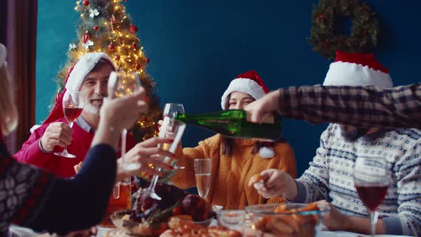 Man Pours Champagne Into Glass and Family Clinks Glasses of Wine and Champagne Together