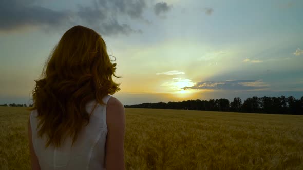 Red Haired Girl Observing Sunset in Wheat Field