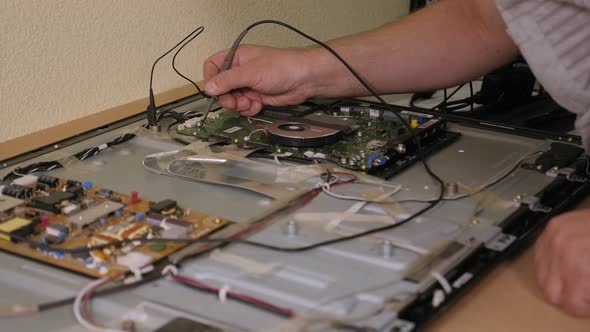 A Technician Checks the Voltage in the Motherboard While Repairing the TV