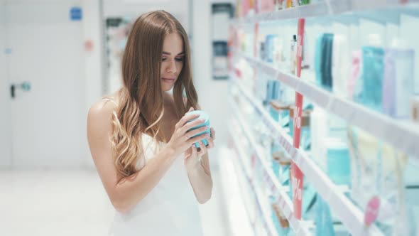 Adorable Young Caucasian Woman Chooses Organic Hand Cream