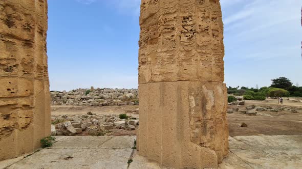 Slow-motion sideways view of Greek temple pillars at Selinunte archaeological park in Sicily, Italy