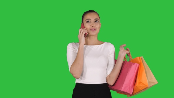 Shopping woman with bags talking on the phone on a Green