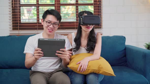 Asian couple using tablet and virtual reality simulator playing games in living room