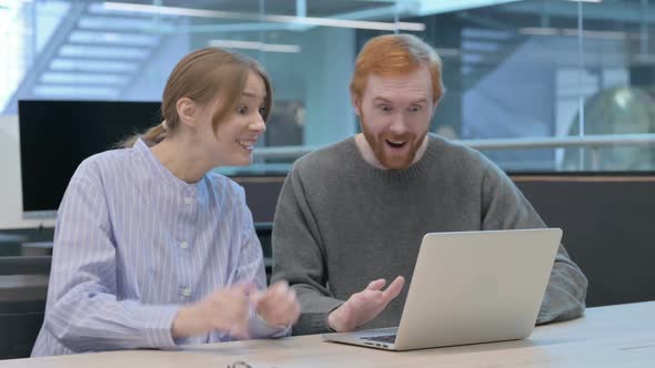 Young Man and Woman Celebrating Success on Laptop