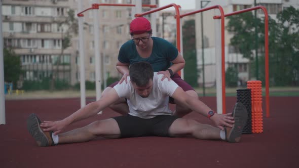 Man and Woman Warming Up and Stretching Before Exercise Outdoor Sports Gym