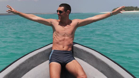 Young Successful Man with Arms Outstretched Enjoying on Deck of Boat at Ocean