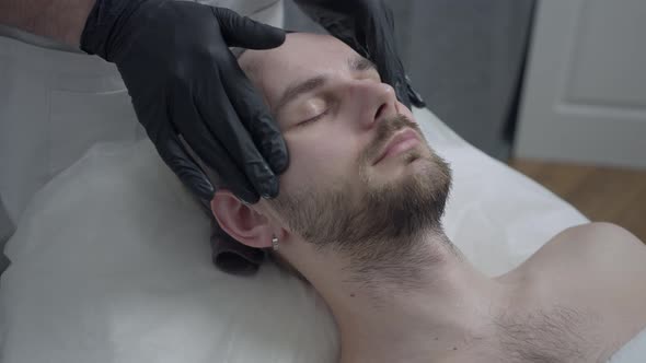 Closeup Facial Massage in Beauty Parlor with Moisturizing Cream for Men