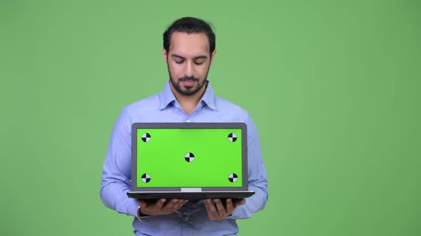 Young Happy Bearded Indian Businessman Showing and Looking at Laptop