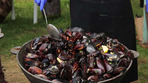 The process of preparing mussels in a large saucepan. Street food with seafood. Close-up.