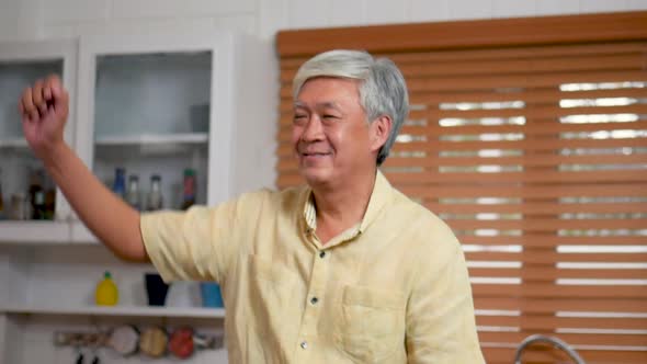 Portrait of Asian senior man happy smiling dancing cooking in the kitchen at home.