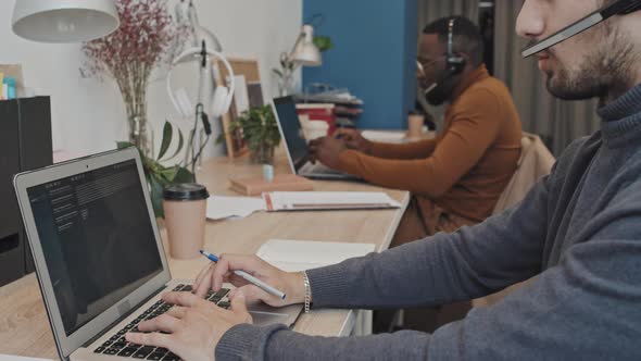 Male Call Center Workers Sitting by Laptops in Office