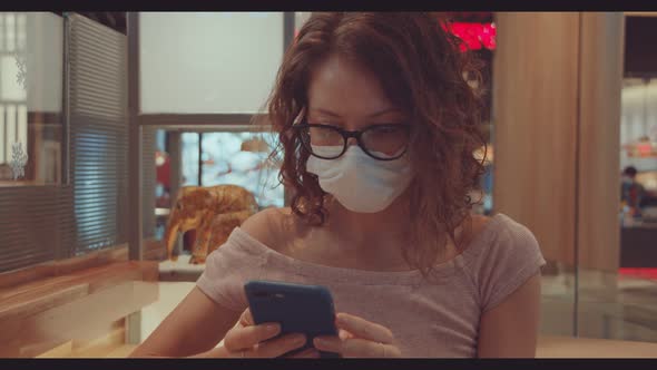 Woman Wearing Face Mask and Using Her Mobile Phone in Shopping Mall