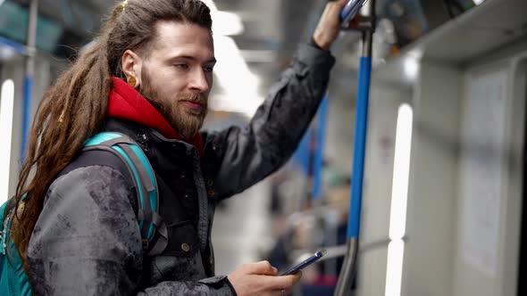 Hipster with Dreadlocks is Riding By Metro Viewing Posts and News in Social Media By Smartphone