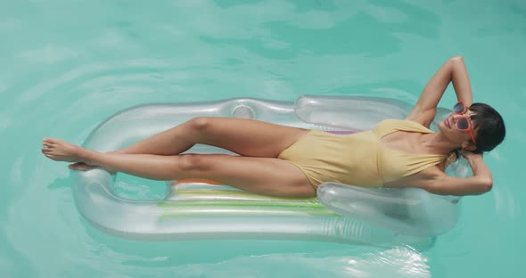 Happy caucasian woman wearing swimming suit with inflatable at swimming pool