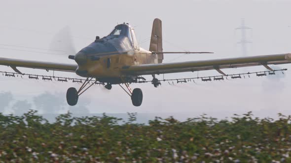 Crop duster spraying chemicals over a cotton field - slow motion