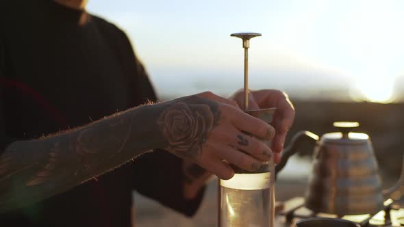 Stylish Man in Black Tshirt with Tattoo on His Arm Putting Ground Coffee Into Glass French Press on