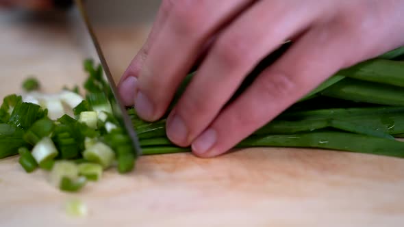Grind Fresh Green Onions on a Wooden Cutting Board in the Kitchen Closeup